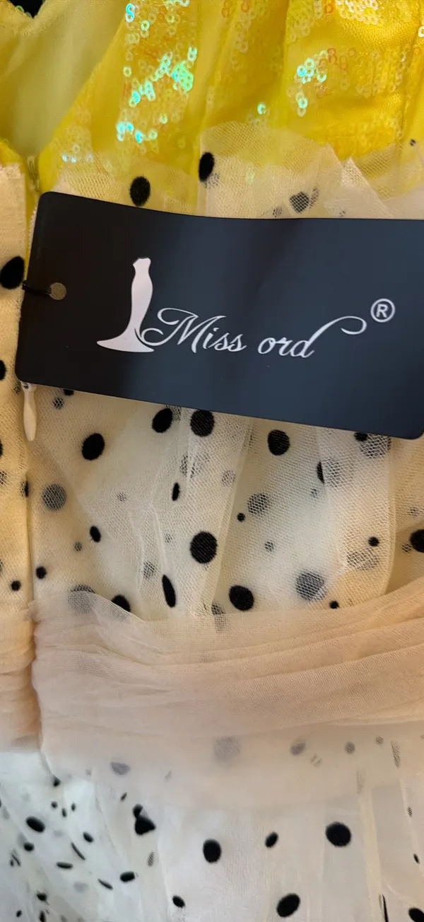 strapless tulle mini dress featuring a cream or light beige mesh fabric adorned with classic black polka dots. It is designed with a heavily ruched, pleated sweetheart bodice, a defined cinched waistband, and a voluminous tiered ruffled skirt. - Image 9