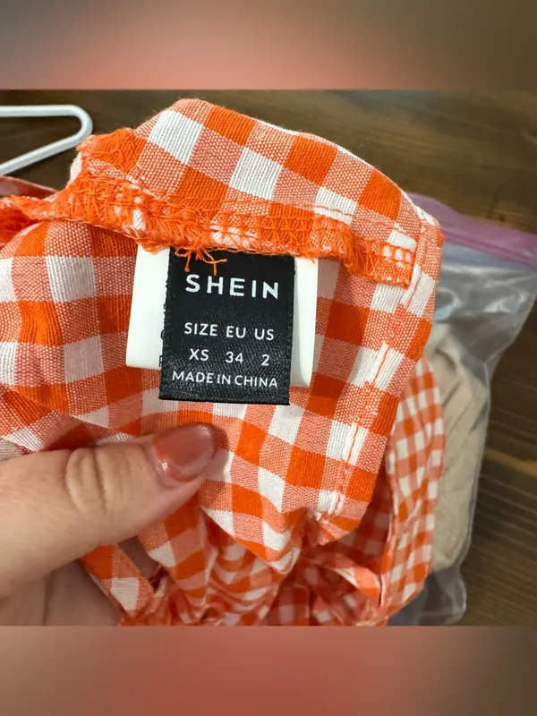 An orange and white gingham crop top with spaghetti straps and a back tie - Image 3