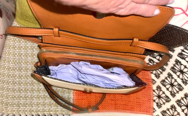 White and brown crossbody bag with adjustable strap. The design features a front flap with a brown leather detail and a clip closure. - Image 4