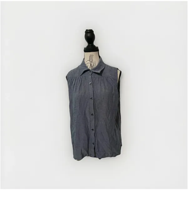 The Cabi Chambray Sleeveless Blouse in blue is a stylish and versatile top perfect for summer, fall, or spring. With a collared neckline, button closure, and ruffle accents, this high-low shirt features a cutout back for added interest. - Image 2