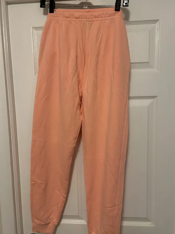 NIKE size small Soft fleece joggers in a warm peach-coral shade. Elastic waistband with adjustable drawstring. Tapered legs with cuffed ankles. Embroidered Nike logo at hip. Cozy everyday women small brand new - Image 3