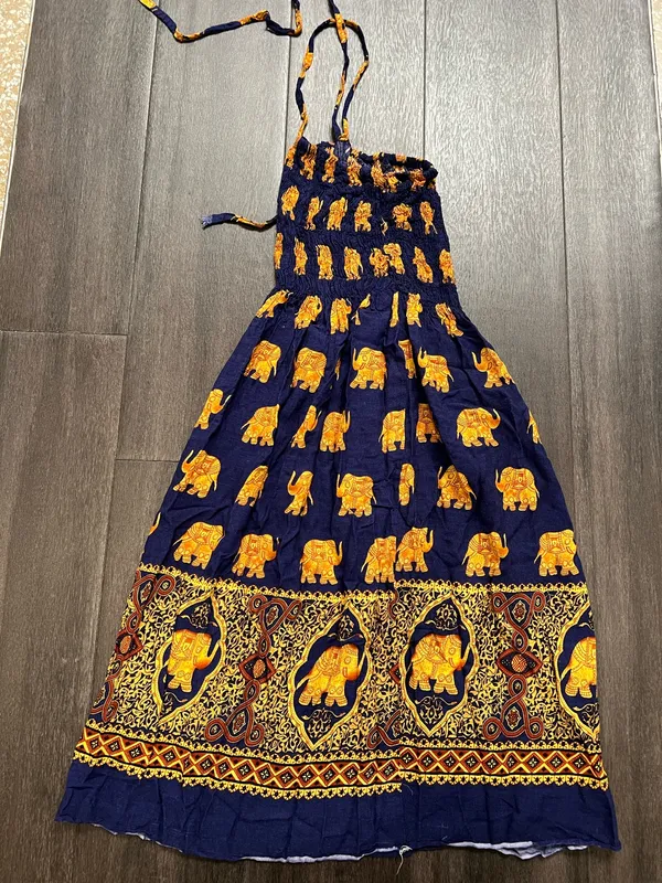 Flowy halter maxi dress with a smocked bodice. Navy base with repeating golden elephant motif. Decorative border print at hem. Lightweight and breezy. Adjustable tie straps. - Image 4