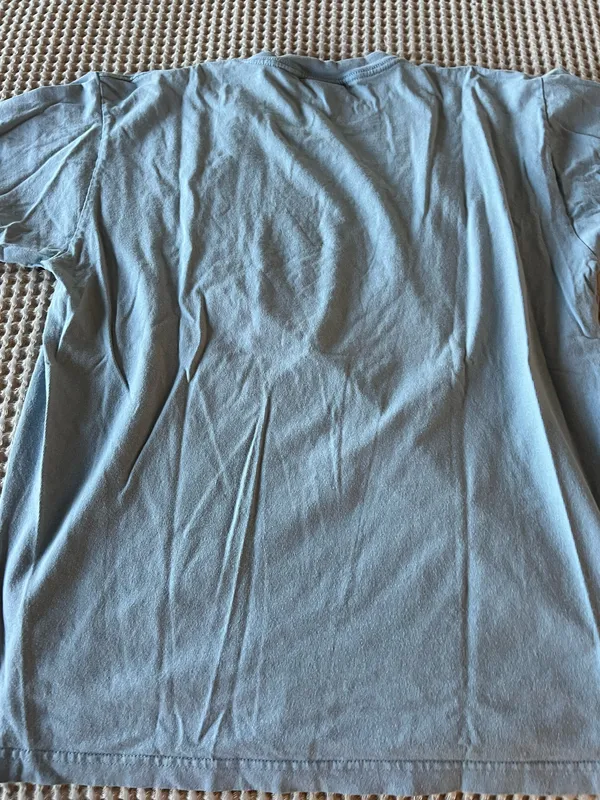 Soft light blue t-shirt. Small circular graphic at chest with teal and navy accents. Casual crew neck style. Easy staple for everyday wear. - Image 3