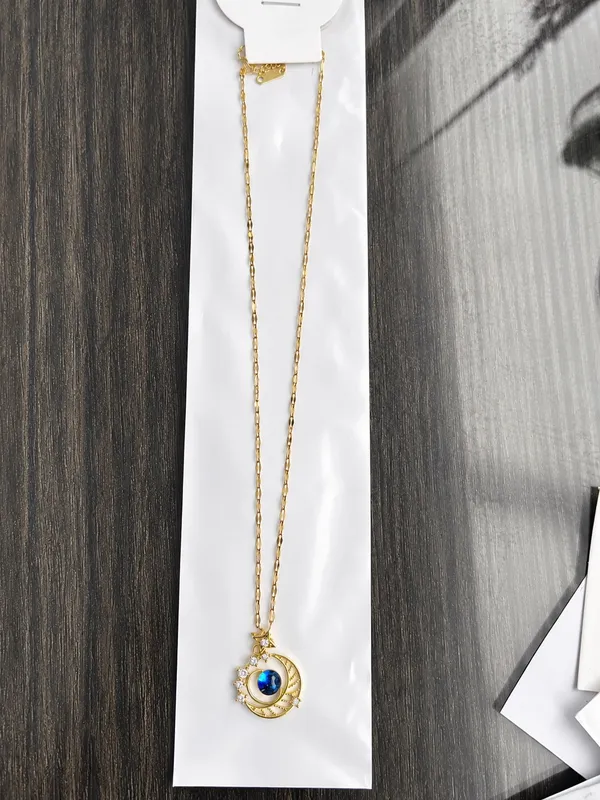 This gold-plated necklace features a celestial-themed pendant with a blue gem representing a planet surrounded by a crescent moon. - Image 2