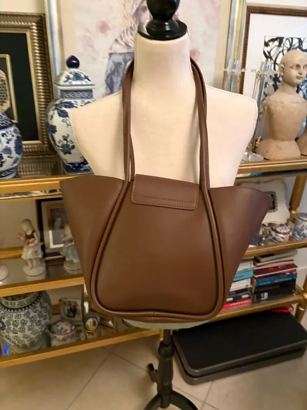 This brown bag features a minimalist design with gold details and a spacious structure. Made from 100% polyurethane, it has a magnetic closure with a gold-tone latch. Designed as a tote or shoulder bag, it's versatile for everyday use or travel. - Image 2