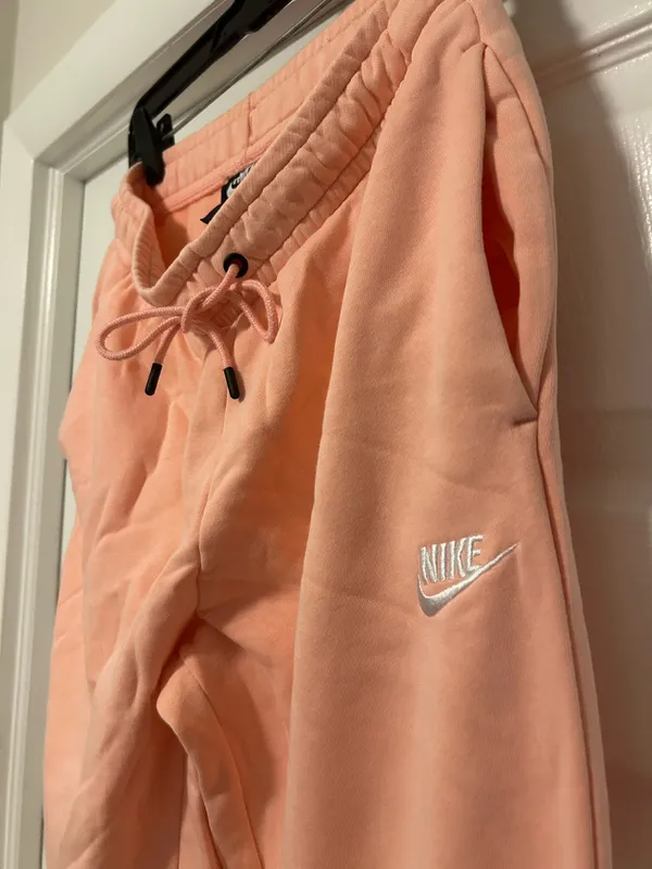 NIKE size small Soft fleece joggers in a warm peach-coral shade. Elastic waistband with adjustable drawstring. Tapered legs with cuffed ankles. Embroidered Nike logo at hip. Cozy everyday women small brand new - Image 4