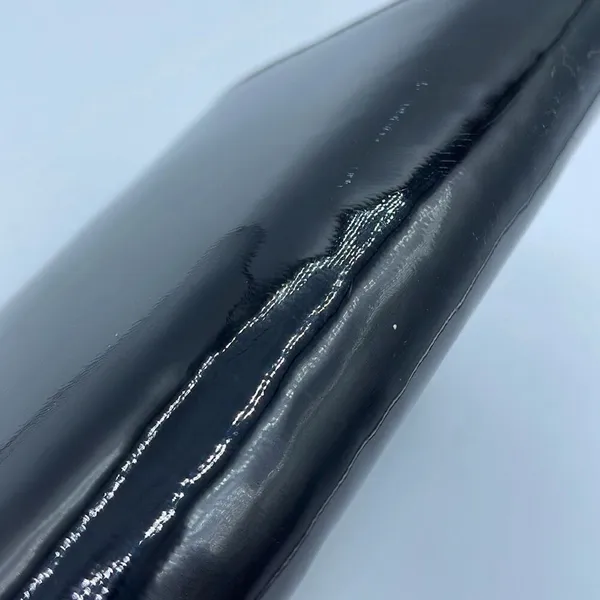 Black faux patent leather clutch with wave design on front. - Image 4