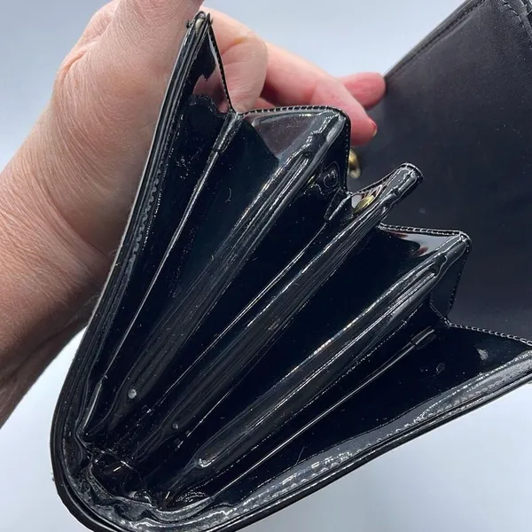 Black faux patent leather clutch with wave design on front. - Image 11