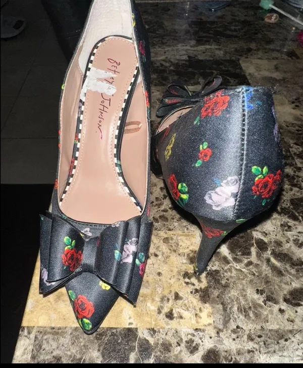 These are Betsey Johnson 'Bret' pumps featuring a black satin upper with a colorful floral print and a prominent bow detail on the pointed toe. - Image 3