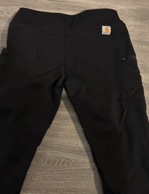 Carhartt women's leggings in solid black. Stretchy fabric for comfort. High waist with secure fit. Side utility pocket for convenience. Durable construction for work or daily wear. - Image 2
