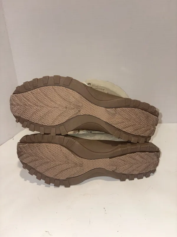 U.S. Polo Assn. Women's Yvonne Snow Boots in an "Oatmeal" or beige colorway. These mid-calf winter boots feature a duck-toe rubber shell base for slush protection, a quilted canvas shaft, traditional lace-up closure, and a plush faux-fur collar trim. A signature metallic logo plaque is attached to the side strap - Image 6