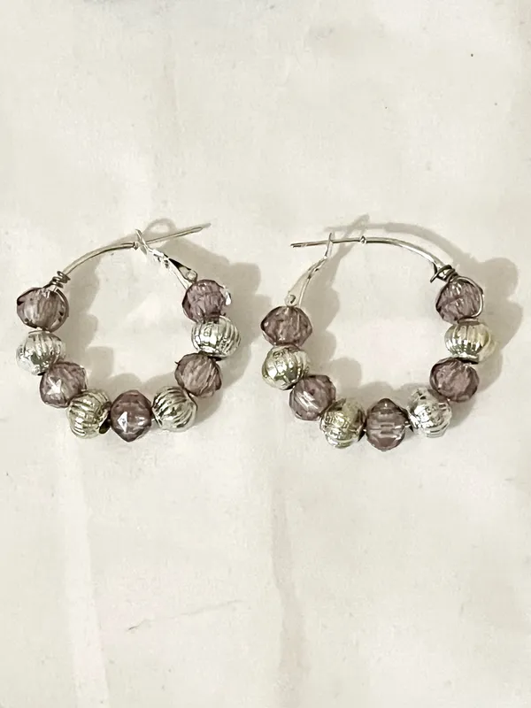 These handmade beaded hoop earrings feature a unique combination of purple, gray, and silver tones. The faceted beads add a touch of bohemian style, making them a perfect gift for someone who loves one-of-a-kind accessories. The handmade quality adds a personal touch to these earrings, making them a standout piece for any jewelry collection. - Image 6