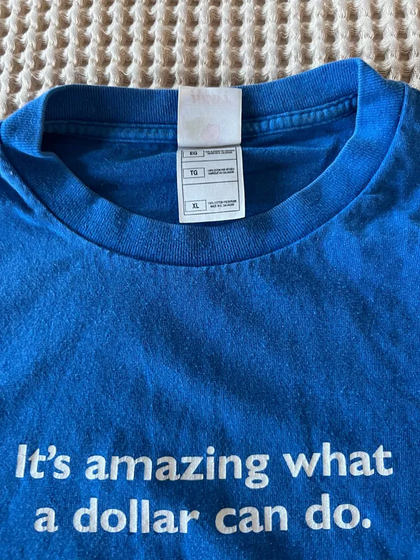 Comfortable blue short-sleeve shirt with white centered text that reads "It's amazing what a dollar can do." Soft, breathable cotton blend for everyday wear. Crew neckline and relaxed fit for easy styling. Blue color adds a bold pop to casual outfits. - Image 2