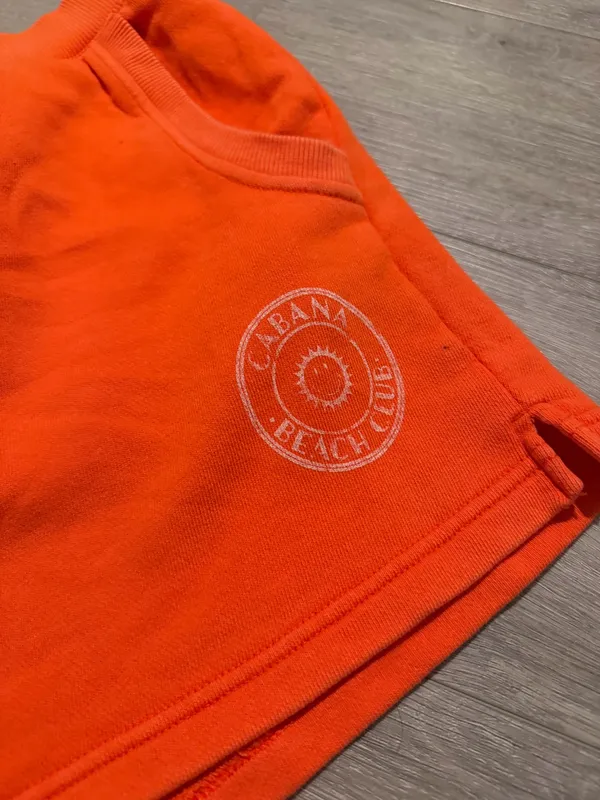 Aerie x Smiley Orange Sweat Shorts - Size XL (Like New) Description: Upgrade your loungewear with these vibrant, bright orange Aerie x Smiley fleece sweat shorts! As seen they feature a comfy elastic waistband, handy side pockets, and a cute "Cabana Beach Club" smiley logo on the left hem. Condition: Excellent, like-new condition with no visible flaws Size: XL / TG Details: Soft fleece lining, perfect for beach days or casual lounging. Close-up of the graphic logo can be found Super cozy and ready for a new home! Fast shipping. - Image 2