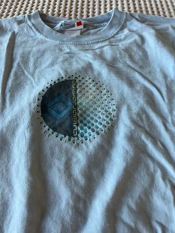 Soft light blue t-shirt. Small circular graphic at chest with teal and navy accents. Casual crew neck style. Easy staple for everyday wear. - Image 2