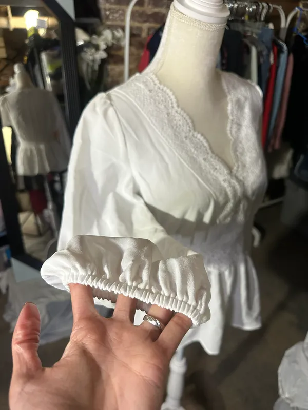 LOS ANGELES white lace V-neck long sleeve shirt top peplum tie cuff New with tag Smoke and pets free Same day shipping Elevate your wardrobe with this stunning white lace blouse from . The V-neckline and long sleeves add a touch of elegance to this top, while the peplum and tie cuff details create a flattering silhouette. The angel character and rose theme make it perfect for any occasion, from casual outings to formal events. Crafted from high-quality lace fabric, this blouse features adjustable features and is available in size S. The solid pattern and delicate lace accents make it a versatile piece that can be paired with any bottom. Whether you're dressing up or down, this Rose & Grey blouse is sure to turn heads. - Image 6