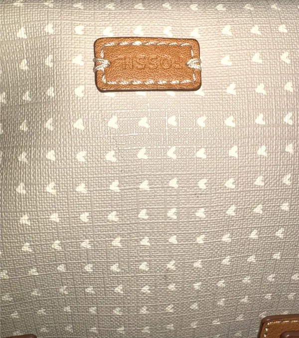 The Fossil Emma Satchel bag in white and gray with a polka dot print and brown leather handles stands out for its classic key charm. - Image 2