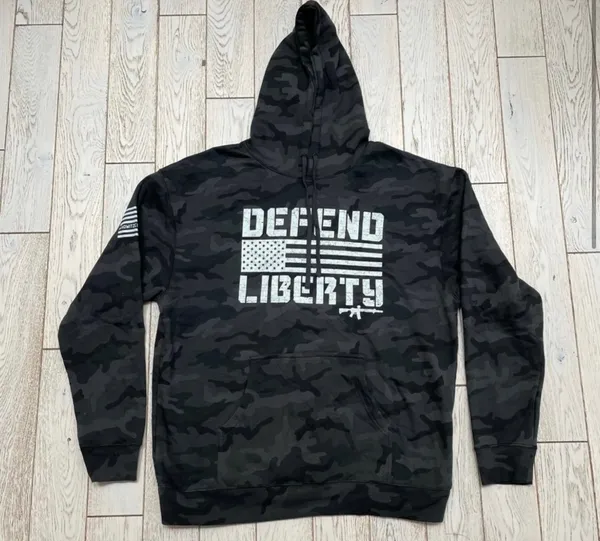 Howitzer "Defend Liberty" Black Camo Hoodie Elevate your casual wear with this rugged and patriotic Howitzer "Defend Liberty" Hoodie. Featuring a stealthy black multicam (camo) pattern, this hoodie is designed for those who value both style and a strong message of freedom. Constructed with high-quality, durable fabric, it offers a comfortable fit perfect for outdoor adventures, range days, or daily wear. Product Features: • Brand: Howitzer Manufacturing Co. • Design: Bold "DEFEND LIBERTY" distressed graphic with the American flag and an AR-15 silhouette on the front. • Back Detail: A vertical "DEFEND LIBERTY" spine graphic for a unique look from every angle. • Sleeve Detail: Features the Howitzer brand American flag patch on the sleeve. • Pattern: Modern black/dark grey camouflage. • Style: Pullover with adjustable drawstring hood and a spacious kangaroo front pocket. - Image 4