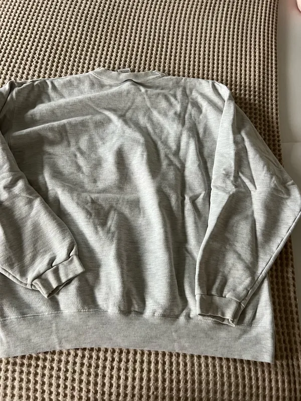 Comfortable light gray crewneck sweatshirt with a small embroidered crest on the chest. Soft, durable fabric for everyday wear. Ribbed cuffs and hem provide a secure fit. Neutral light gray pairs easily with casual outfits. - Image 4