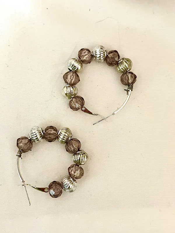 These handmade beaded hoop earrings feature a unique combination of purple, gray, and silver tones. The faceted beads add a touch of bohemian style, making them a perfect gift for someone who loves one-of-a-kind accessories. The handmade quality adds a personal touch to these earrings, making them a standout piece for any jewelry collection. - Image 5
